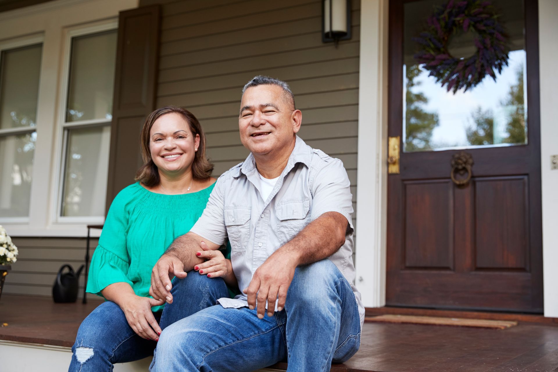 A man and a woman are sitting on the porch of their house.