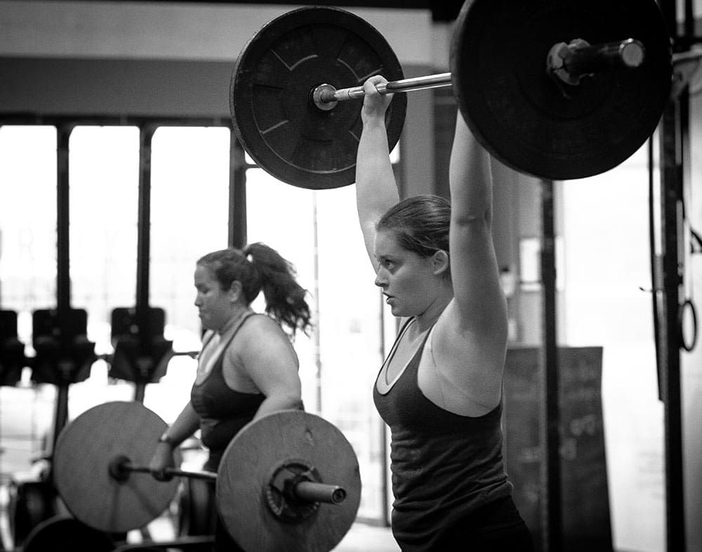 Athletes lifting barbells in a CrossFit class