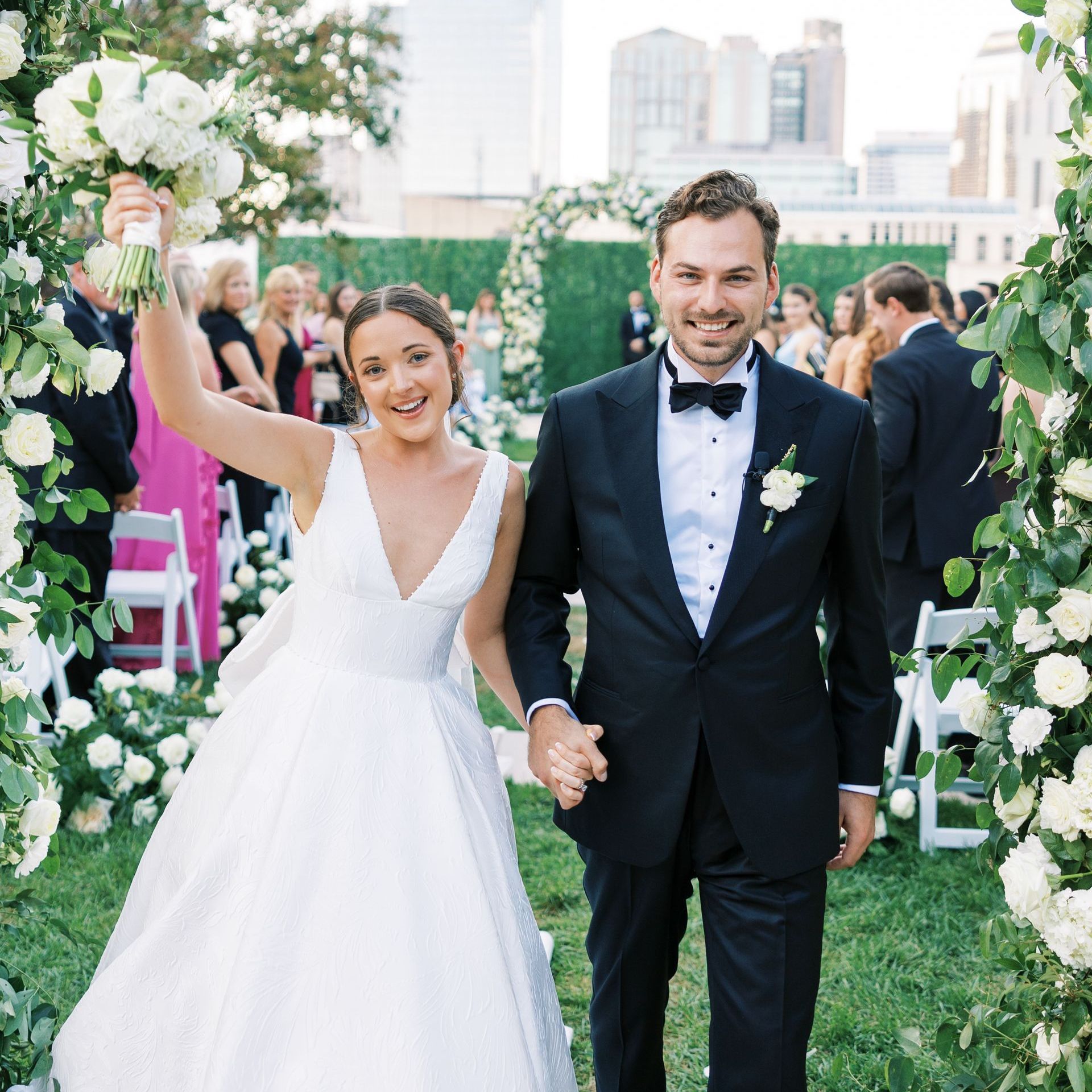 A bride and groom are walking down the aisle at their wedding holding hands by Wedding Planner Nashville