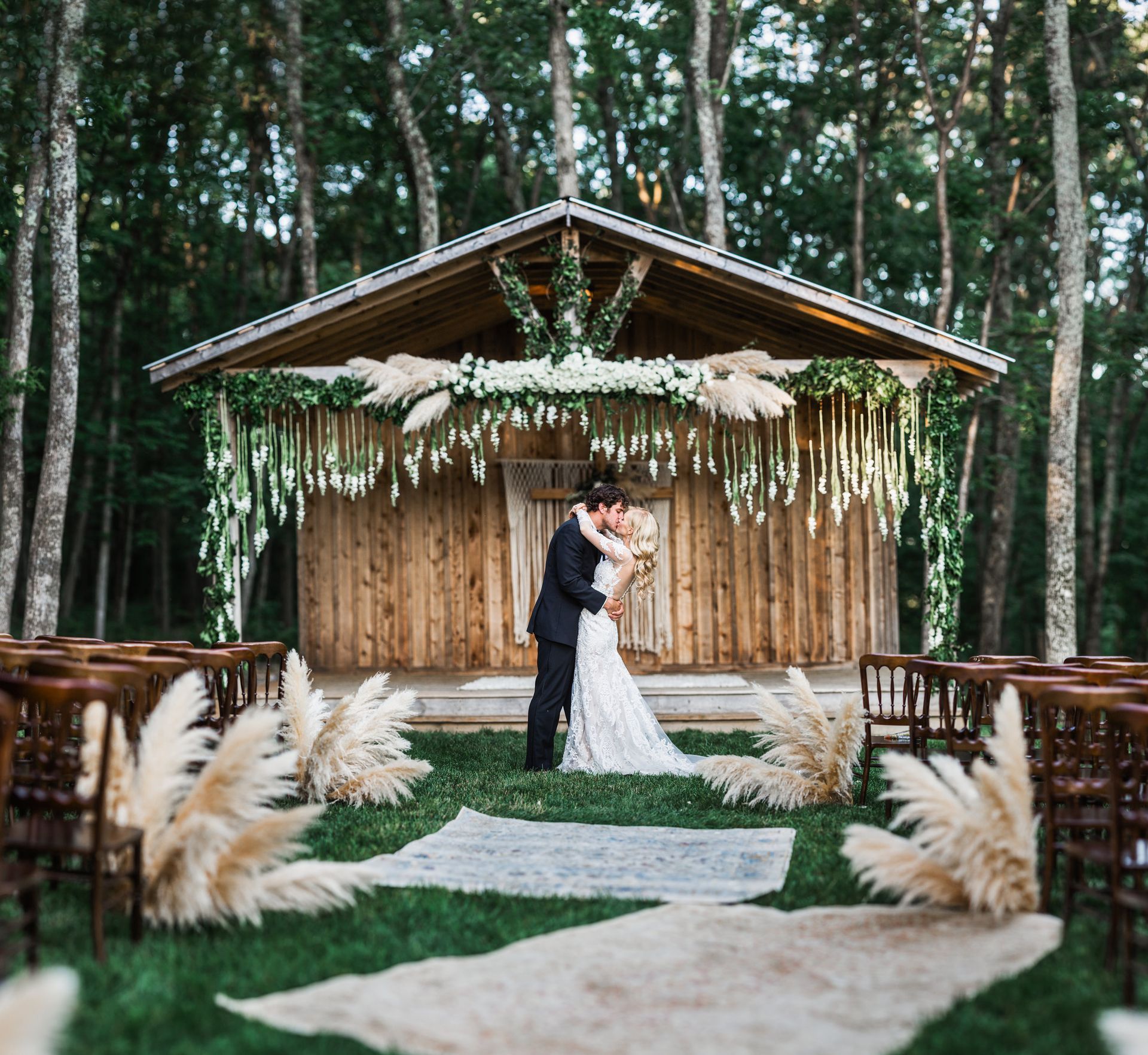Bride and groom kissing in front of a wooden building by Wedding Planner Nashville
