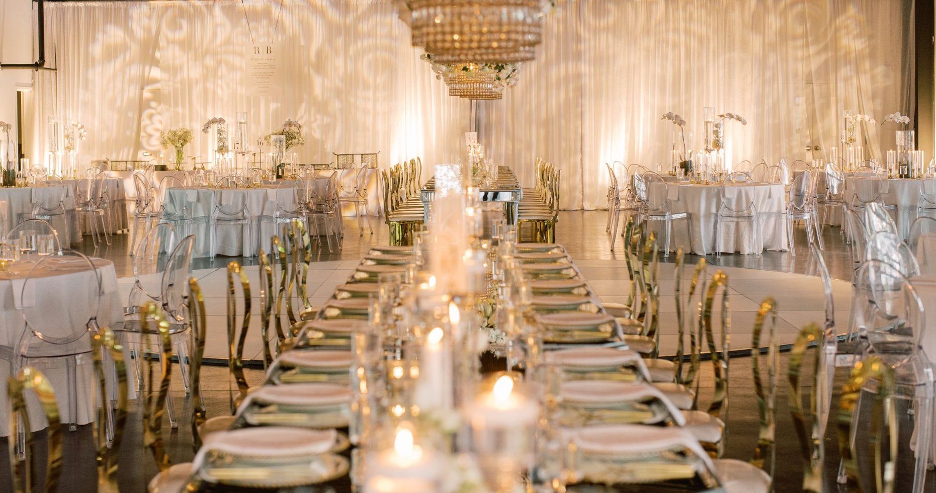 A long table with plates and candles in a large room by Wedding Planner Nashville