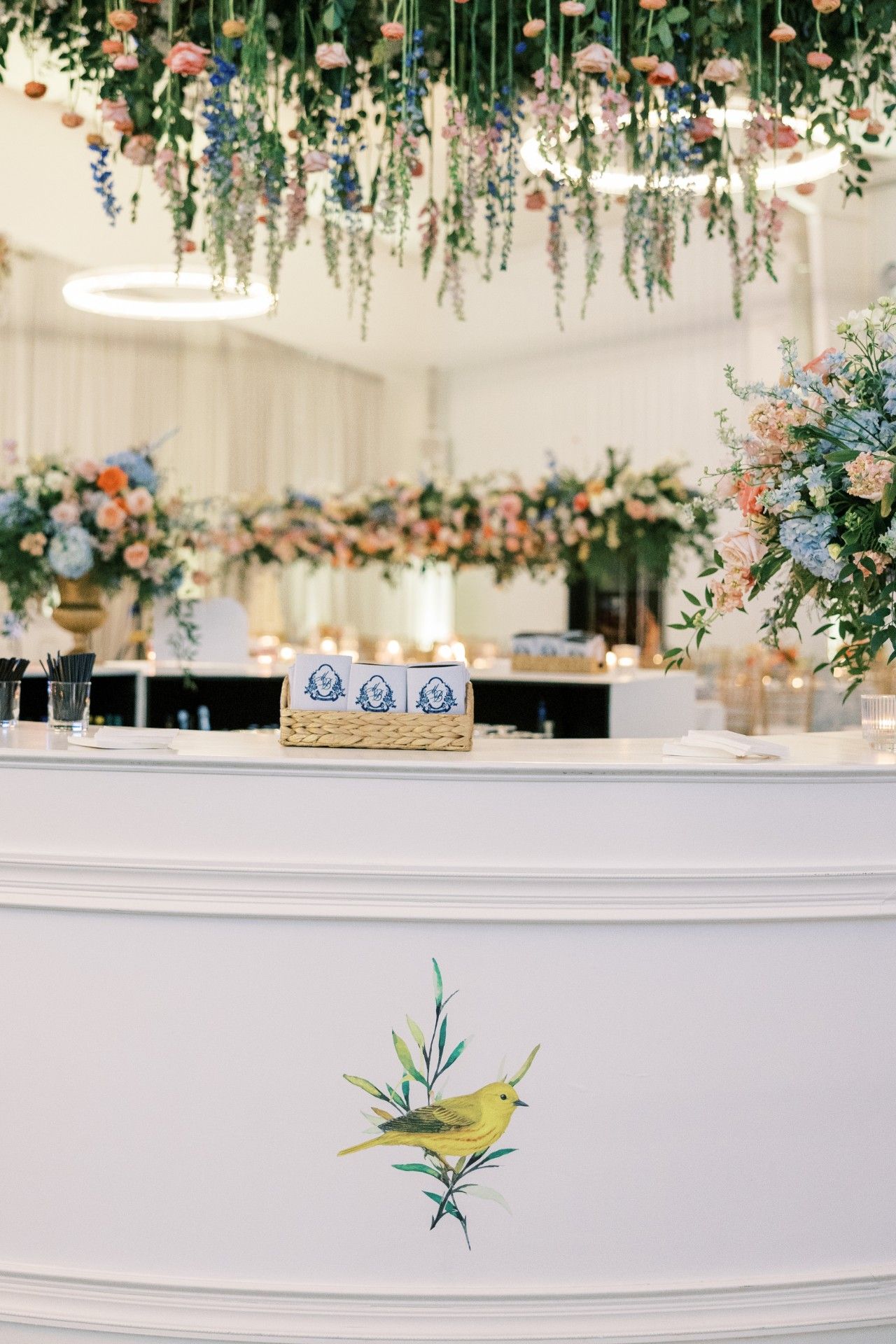 A white bar with a bird on it and flowers hanging from the ceiling by Luxury Wedding Planners in Nashville, TN