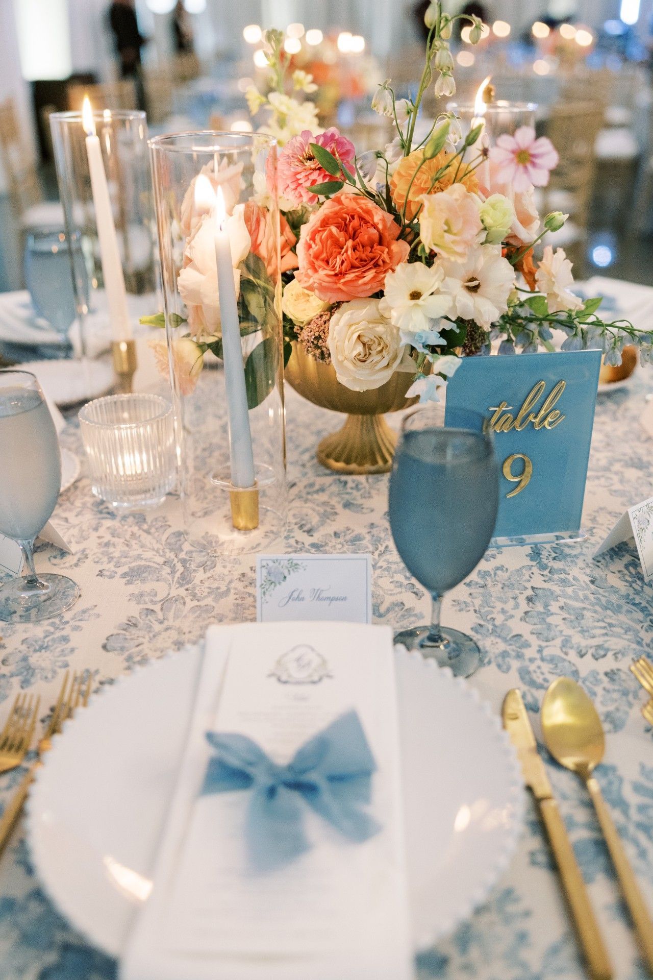A table setting with plates, utensils, candles, and a vase of flowers by Luxury Wedding Planners in Nashville, TN