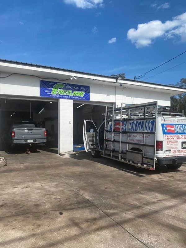 Auto repair shop with a truck and pickup parked outside under a blue sign in bright daylight