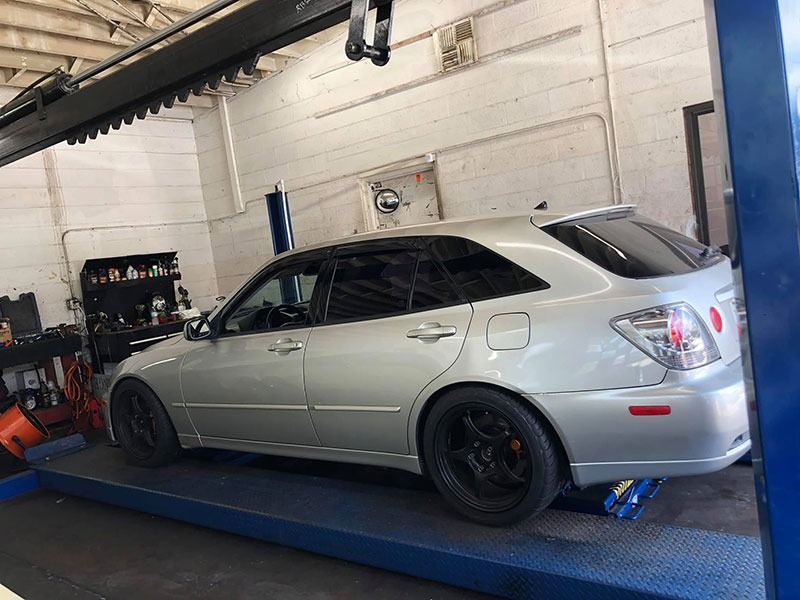 Silver sedan on a blue car lift in an auto shop garage