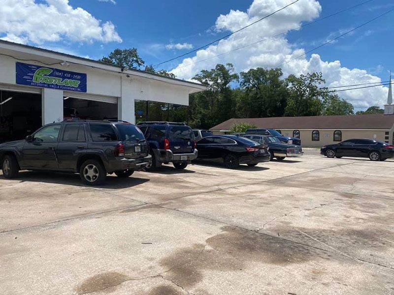 Auto repair shop with several parked SUVs and cars under a partly cloudy sky