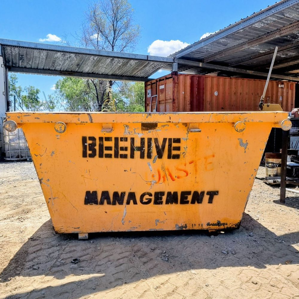 A Yellow Dumpster Filled With Logs and Rocks — Beehive Property Maintenance in Blackwater, QLD
