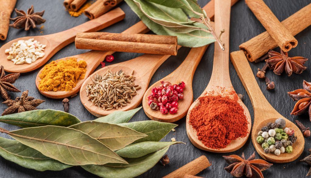 A variety of spices in wooden spoons on a table.