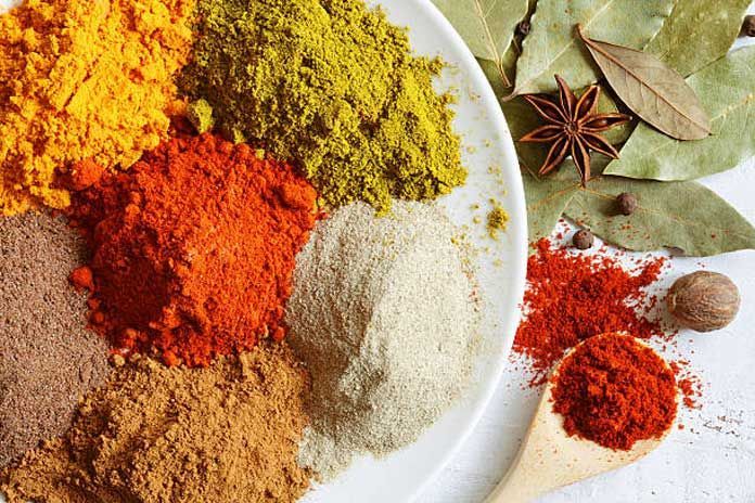 A white plate topped with a variety of spices and a wooden spoon.