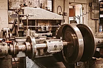 Wire forming machine A machine is sitting in a room with wheels on it.