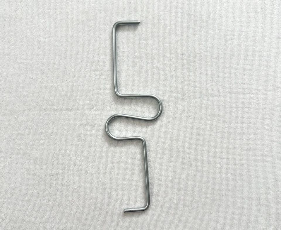 cnc wire forming a close up of a metal wire on a white surface .