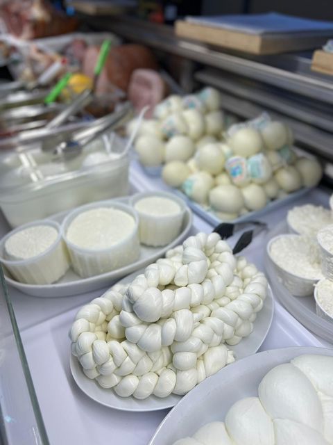 Vetrina con vari formaggi bianchi: intrecciati, rotondi e in contenitori.