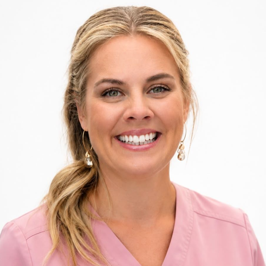 Leende blond kvinna i en rosa topp mot en vit bakgrund