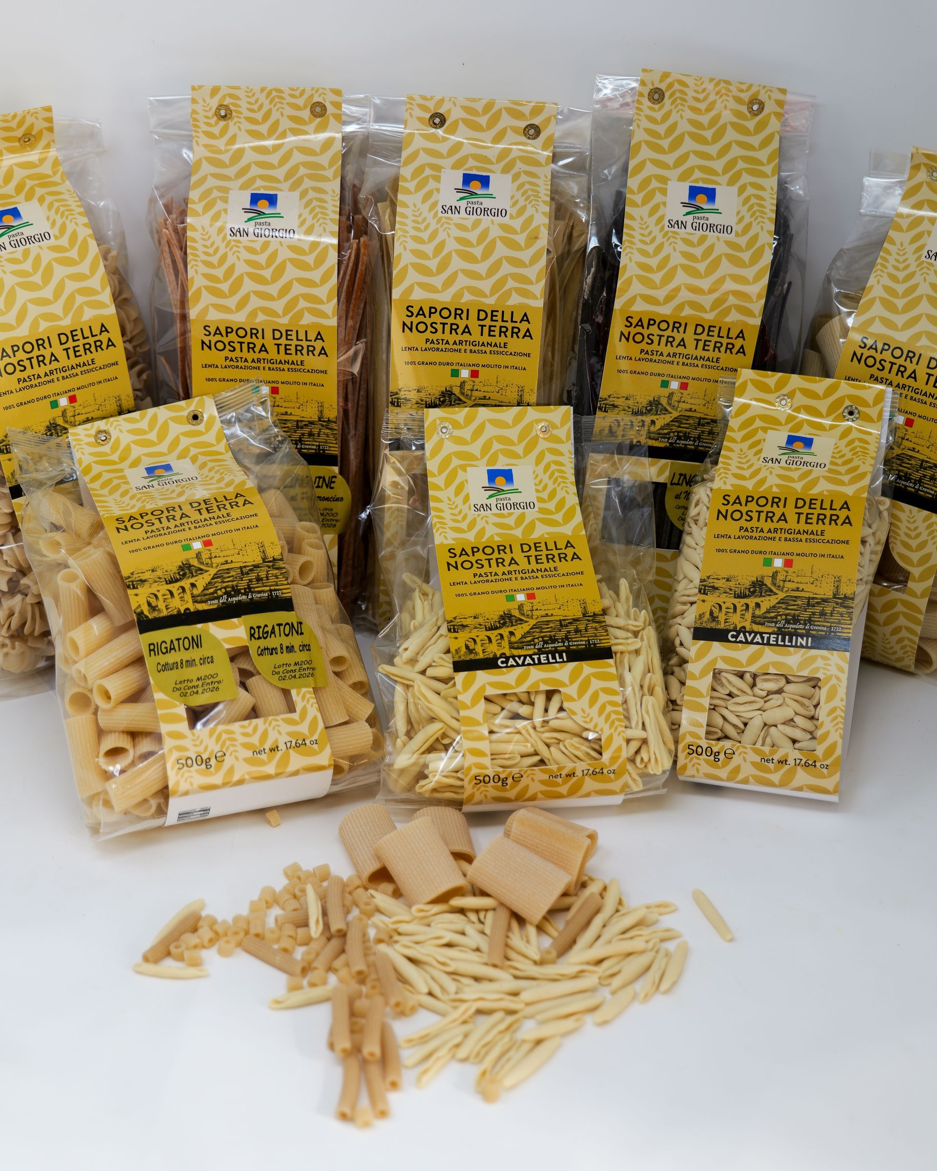 Quadrati di ravioli infarinati e disposti su una superficie di legno.