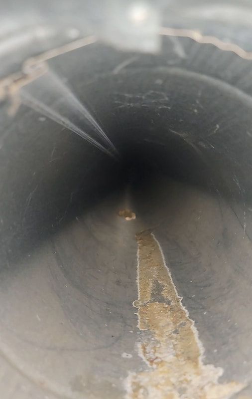 A close up of a metal pipe with water coming out of it.