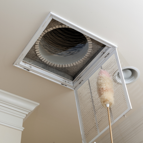 A white air vent is sitting on top of a carpeted floor next to a wall.