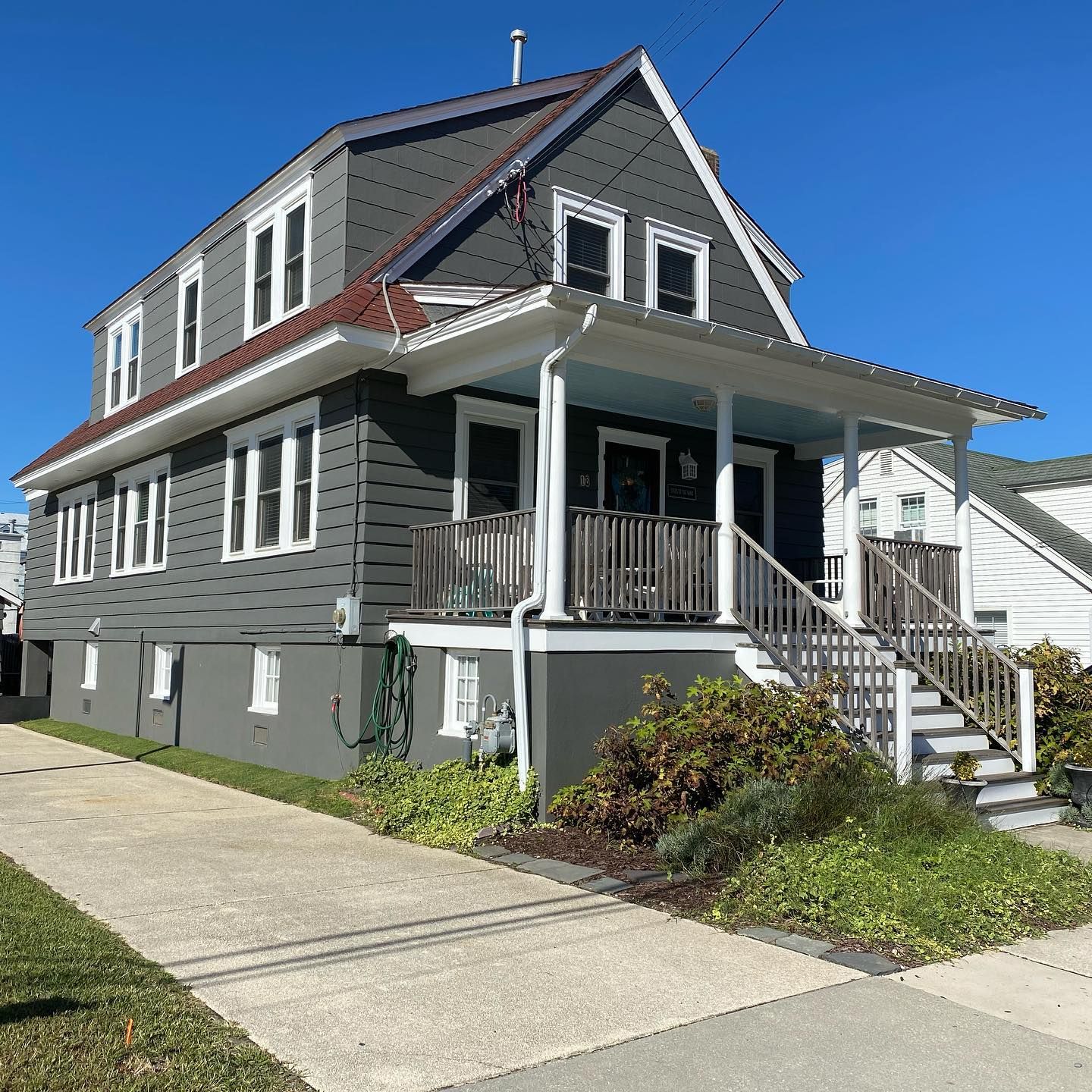 A large grey house with a porch and stairs