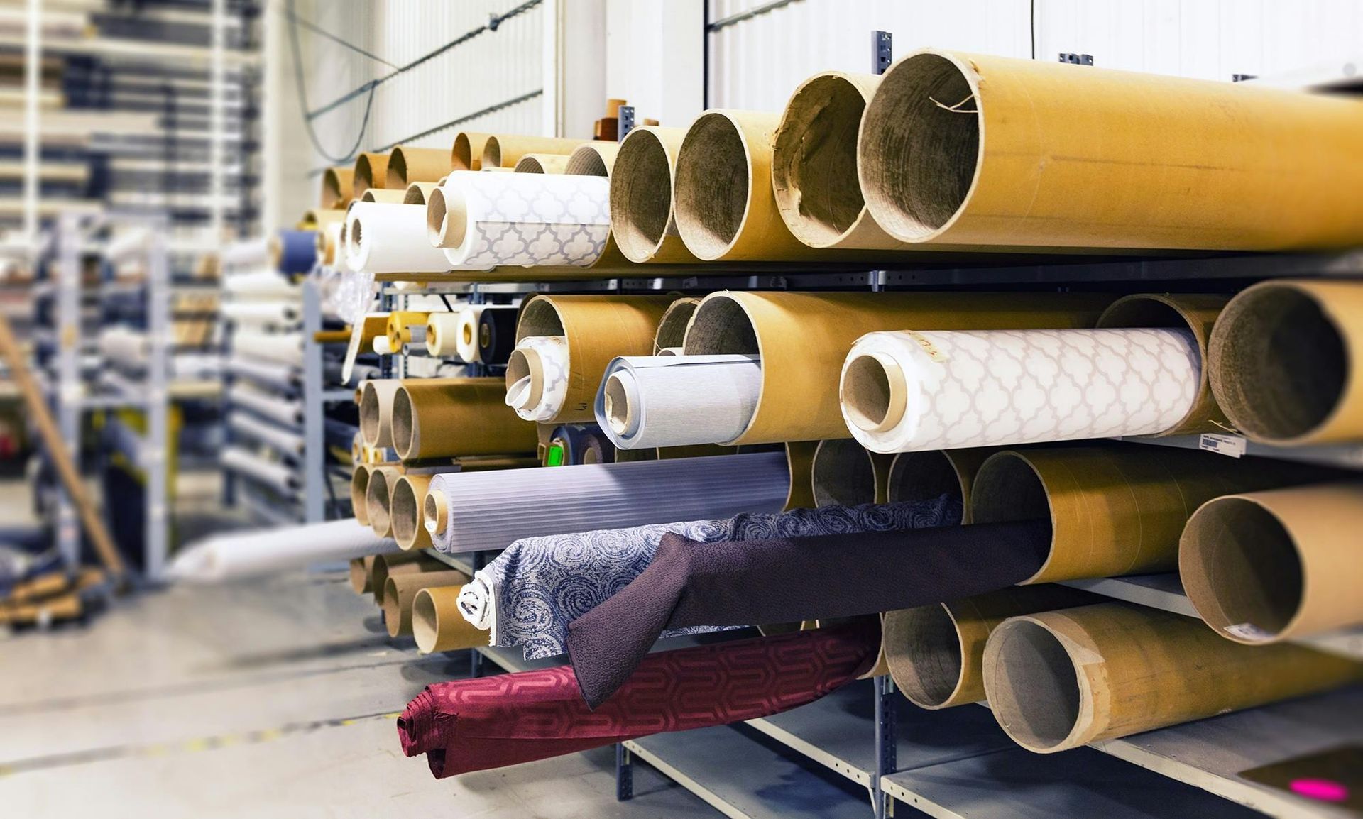 A warehouse filled with rolls of fabric and cardboard tubes.