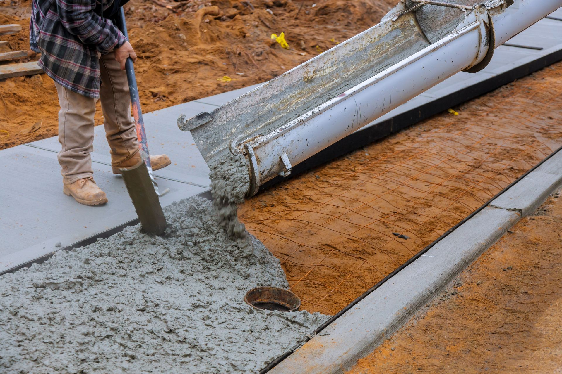 Concrete contractor pouring fresh concrete for sidewalk with chute and leveling tool on site. Concrete contractor pouring fresh concrete for sidewalk with chute and leveling tool on site.