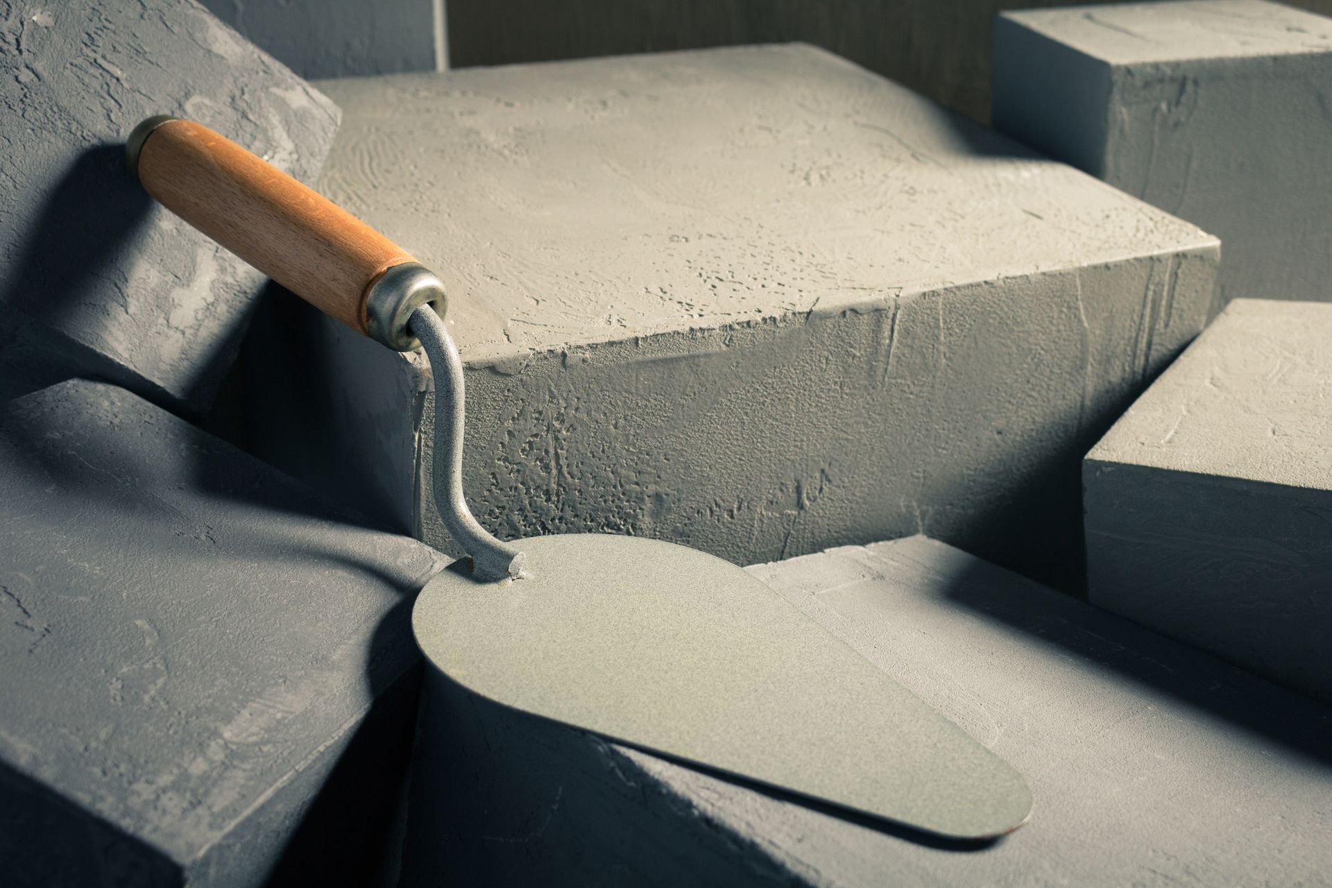 Masonry trowel resting on shaped concrete blocks with rough textured surfaces. Masonry trowel resting on shaped concrete blocks with rough textured surfaces.