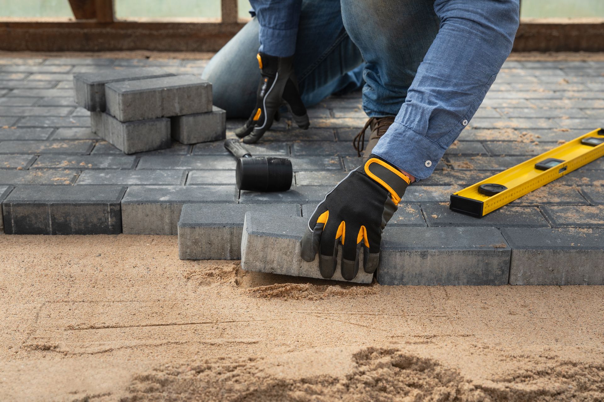 Close-up of a worker's hands expertly installing a block for a concrete construction walkway.