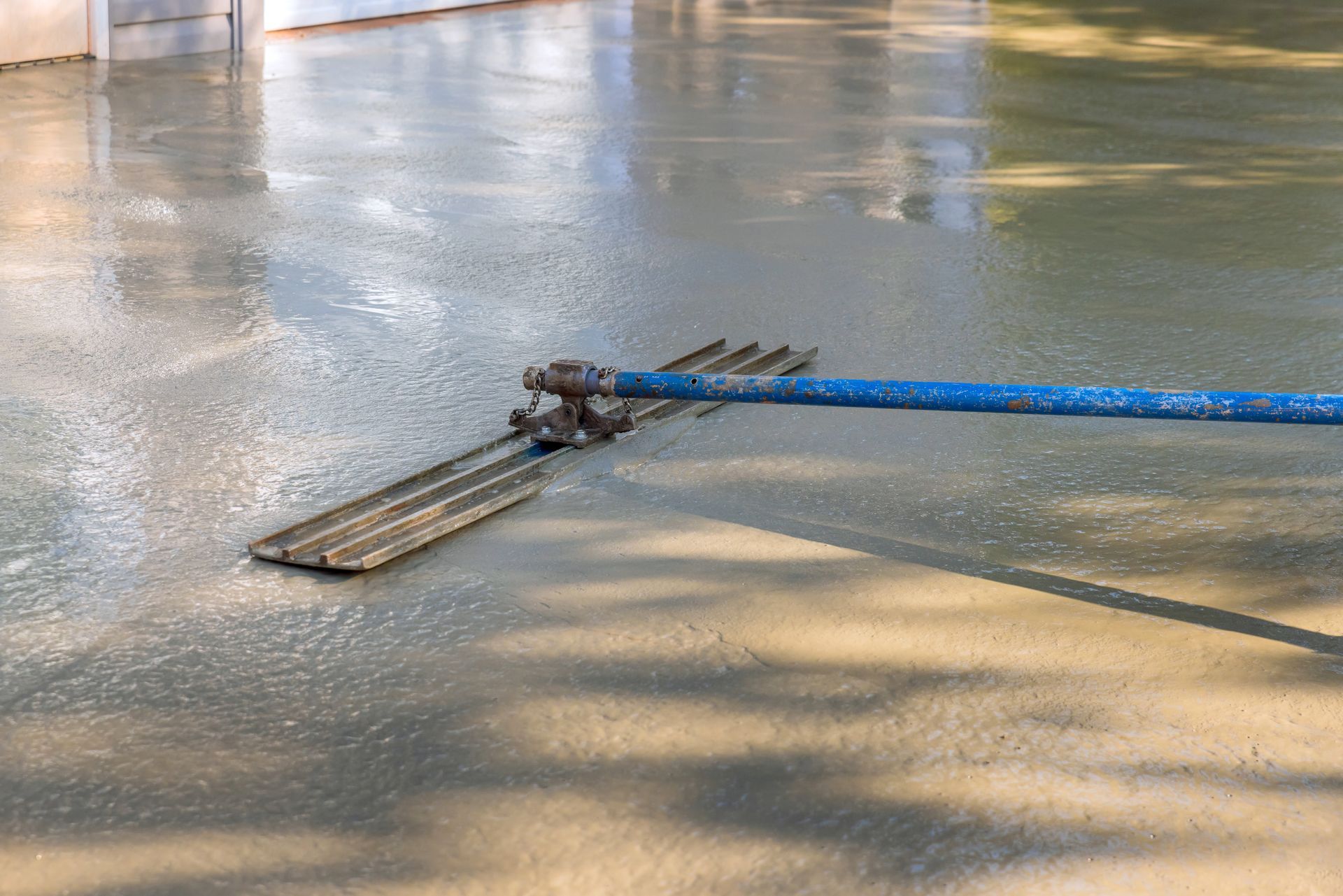 Professional worker using a trowel for smooth concrete construction at sunset.