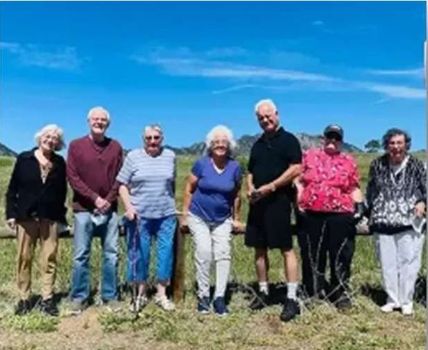 A group of people are posing for a picture in a field.