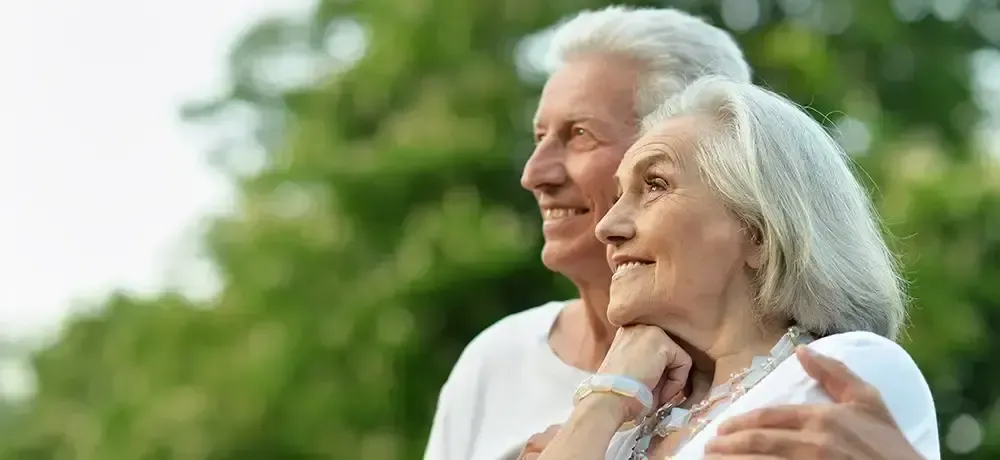 A man and a woman are hugging each other in a park.