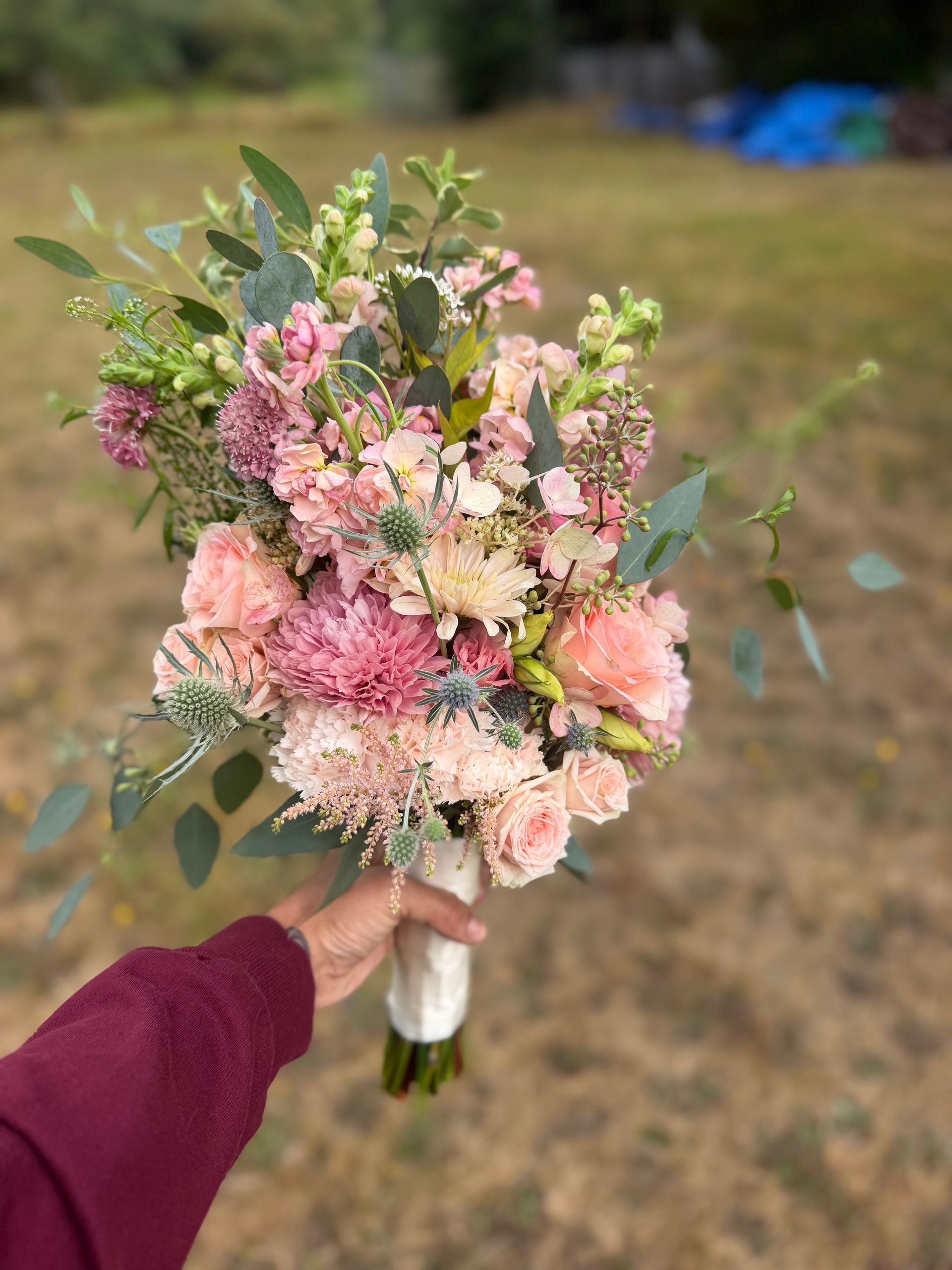 Bouquet of pink and purple flowers with greenery and a white butterfly decoration.
