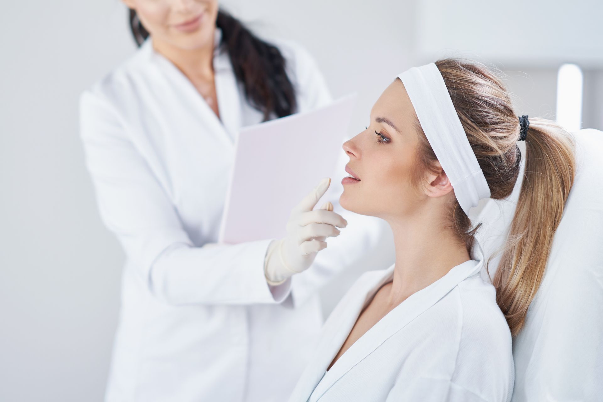 Woman receiving a medical consultation. A medical professional holds a pen near the patient’s face.