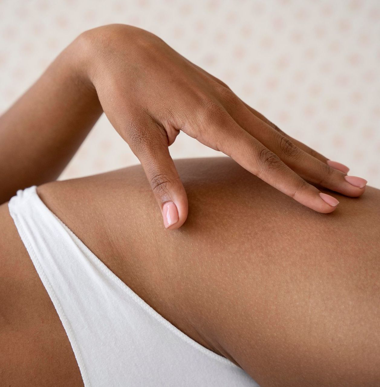Hand resting on a thigh, wearing a white bikini bottom. Light brown skin.