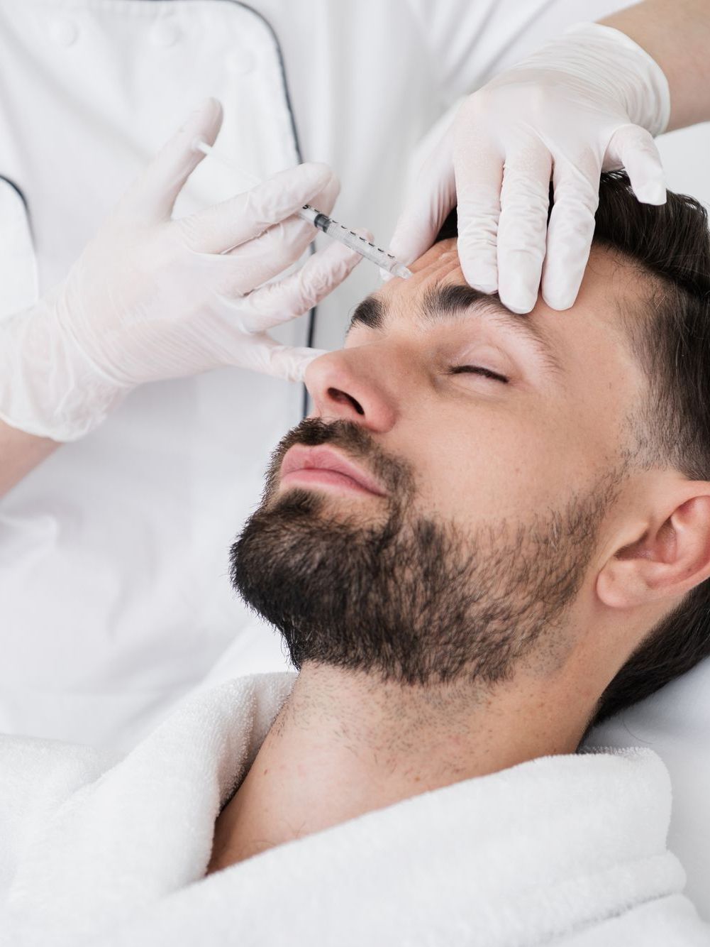 Person receiving a facial injection on the forehead, with gloved hands holding the syringe.