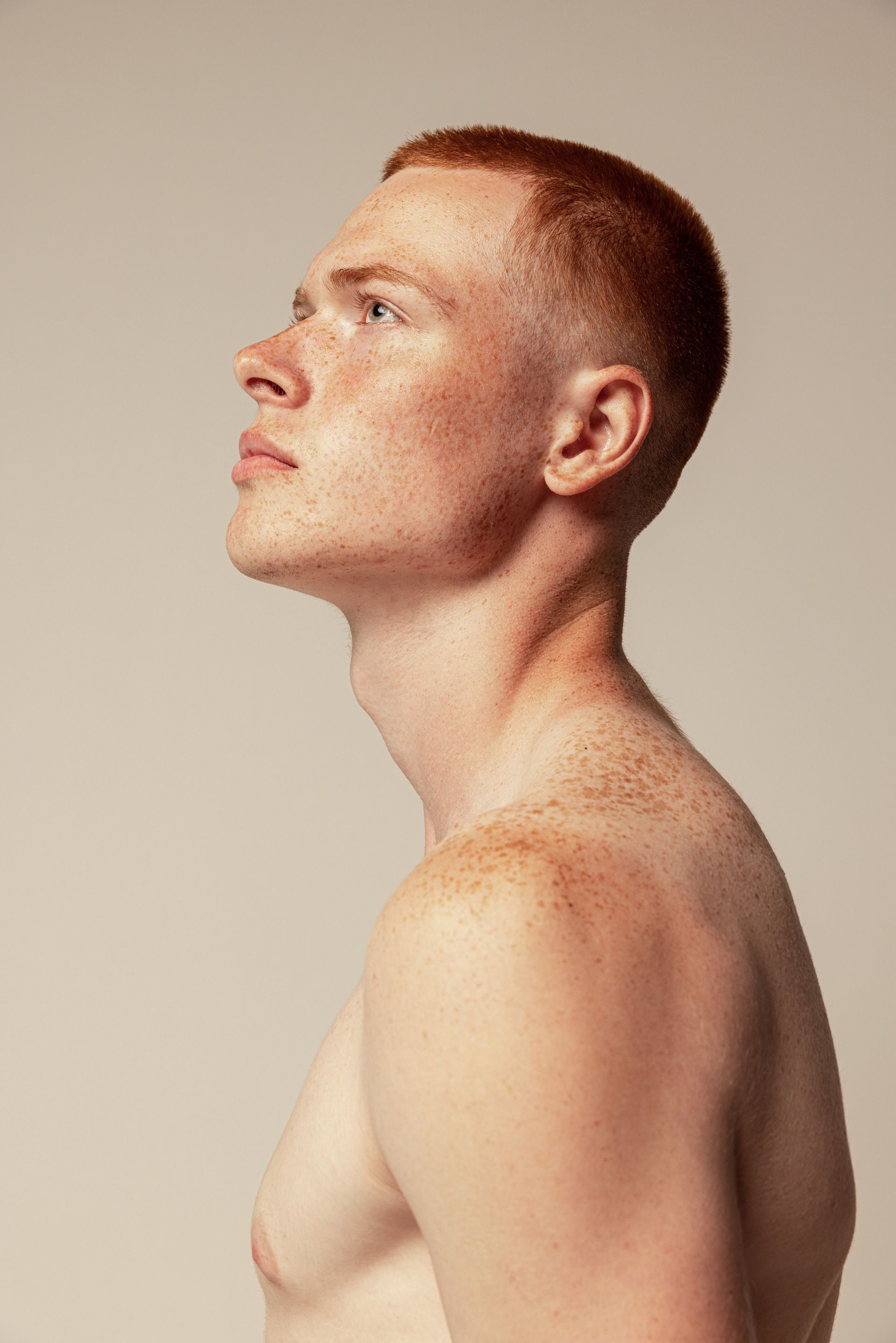 Man with red hair and freckles looking upward, profile view.