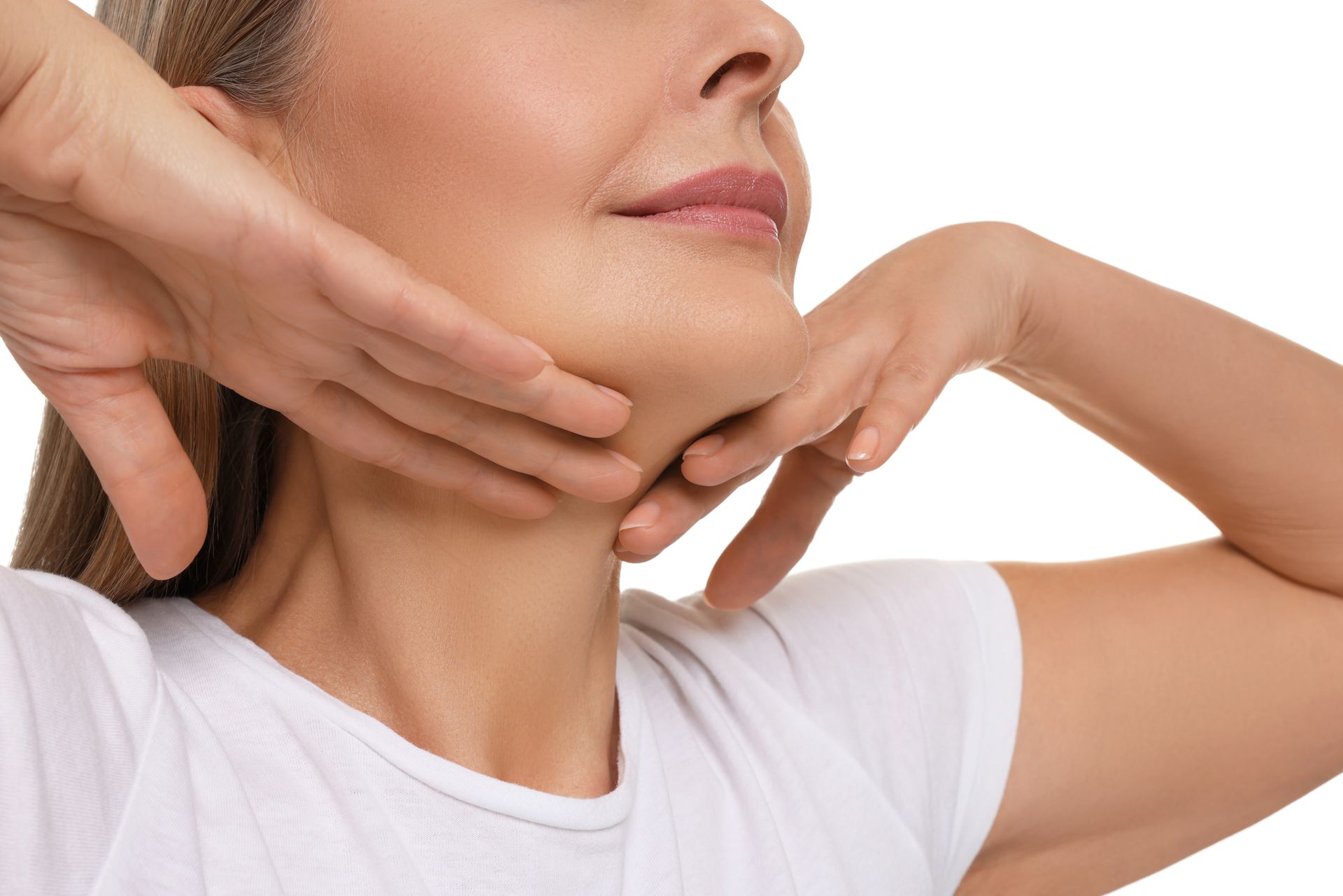 Woman touching neck and jaw with hands, looking upwards, white shirt.