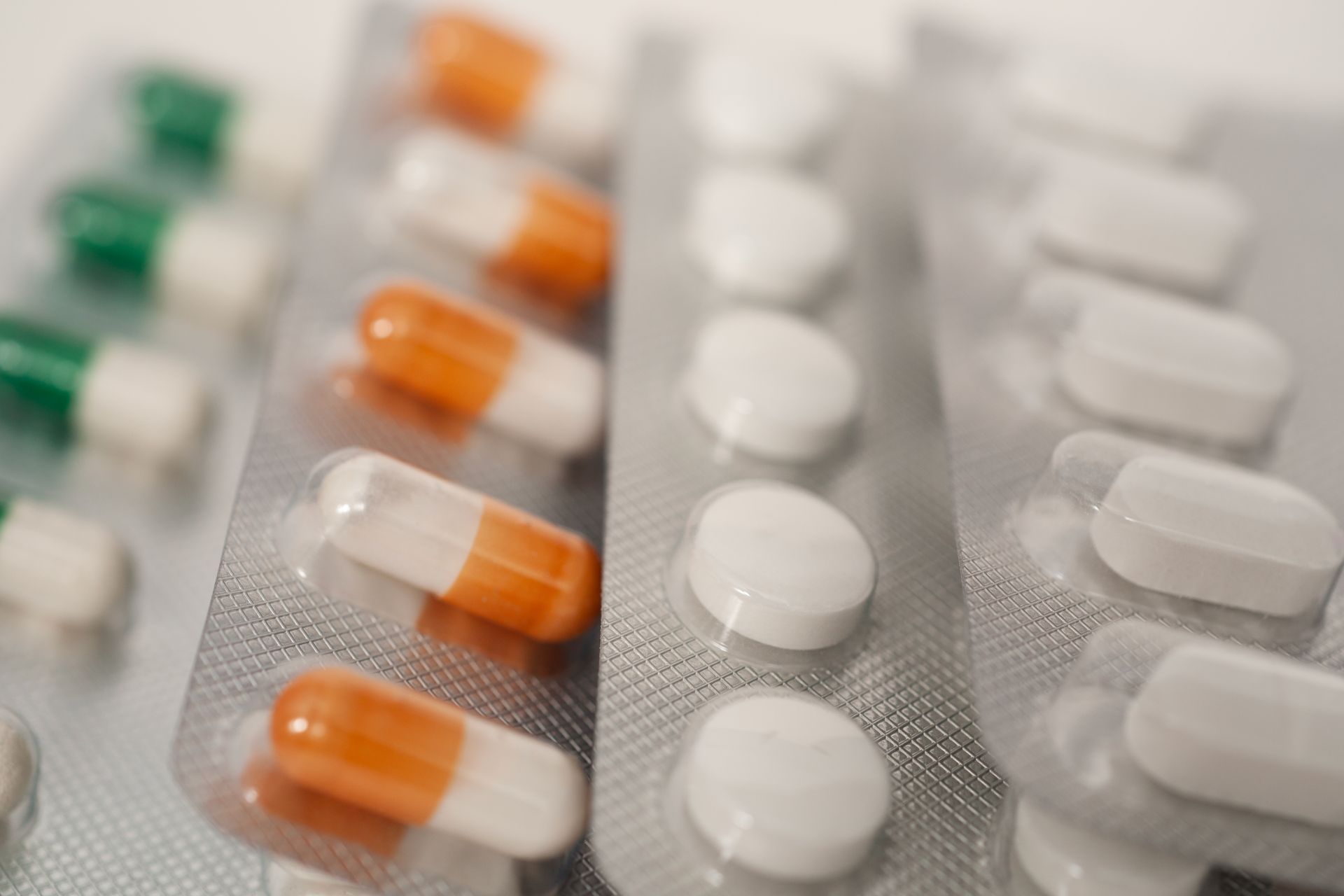 Two clear tubes filled with green capsules, with a silver top, against an orange background.
