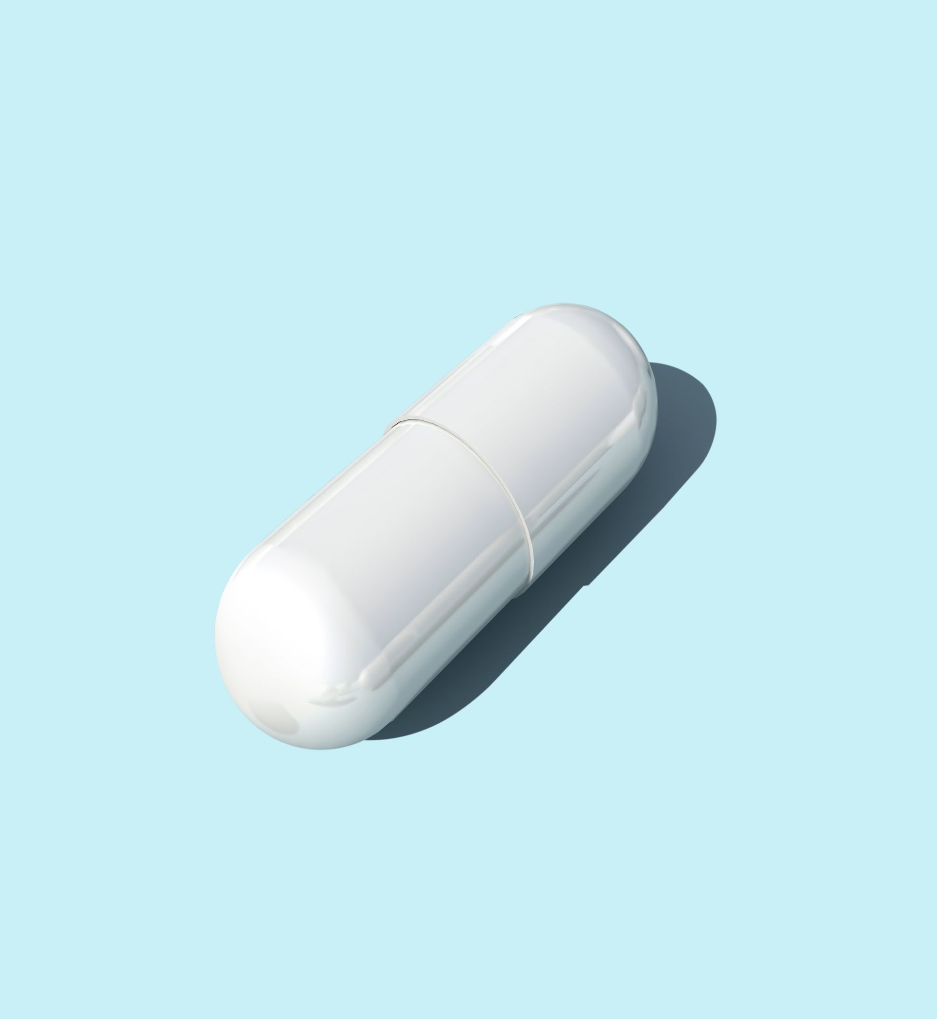 White capsule on a light blue background, showing a shadow.