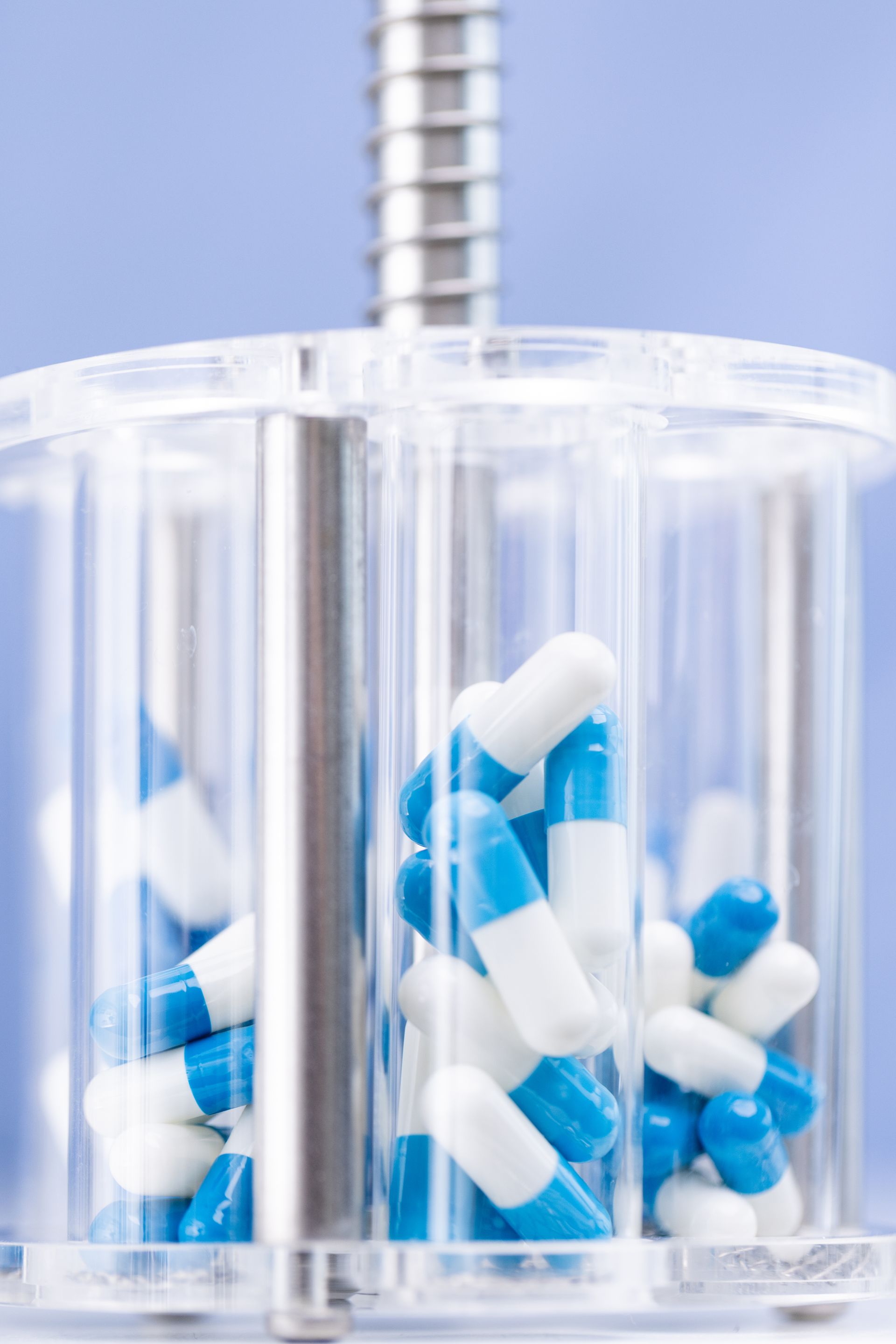 Blue and white capsules inside a clear, cylindrical container.