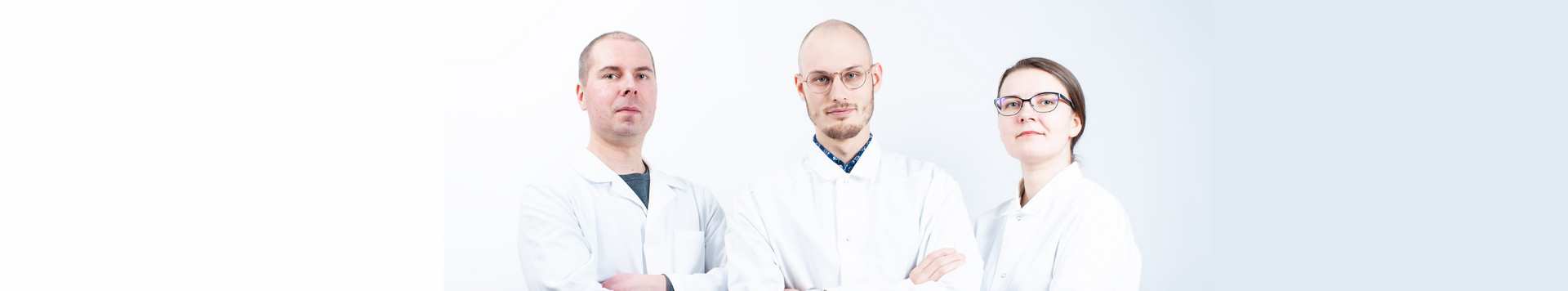Three people in white coats standing in front of a white background.