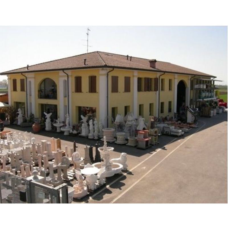 Negozio di statue da giardino e pietre ornamentali all'aperto in un edificio giallo a due piani con articoli esposti all'esterno.