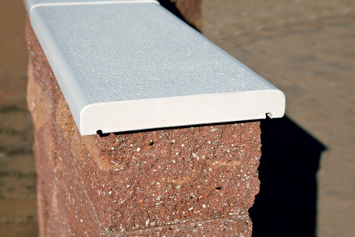 Tappo metallico bianco su un muro di mattoni illuminato dal sole