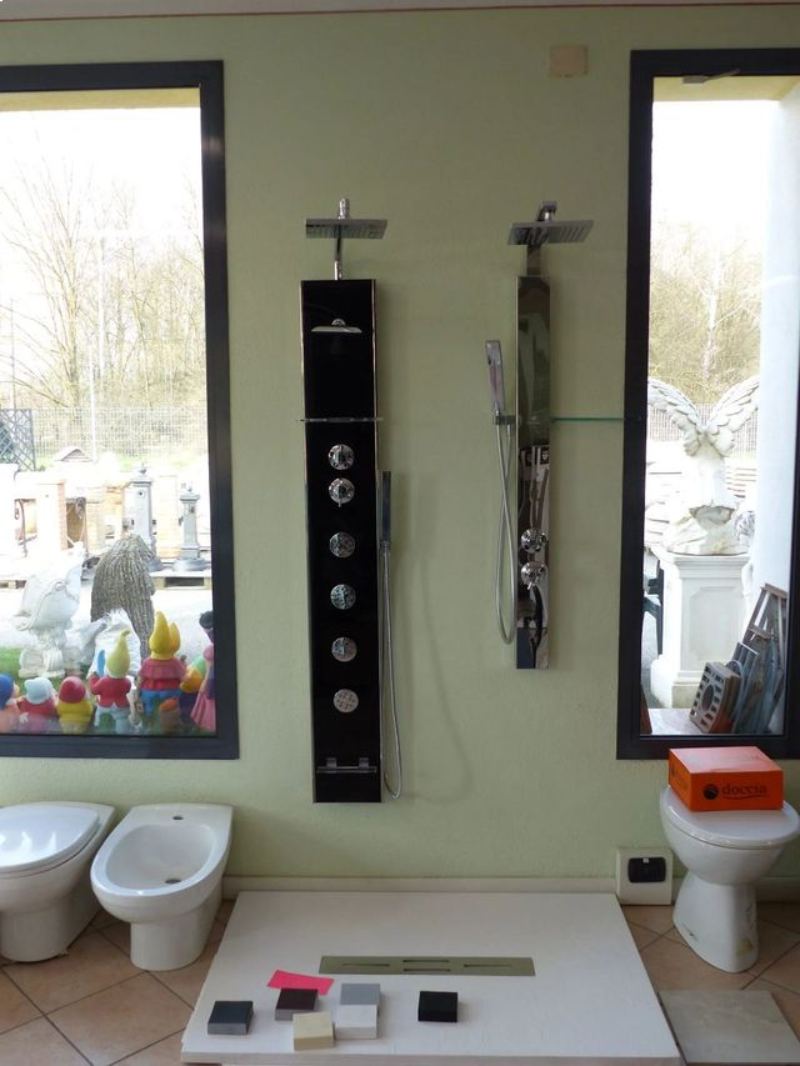 Bagno moderno con due finestre, pannello doccia a parete e bidet bianchi accanto al lavabo.