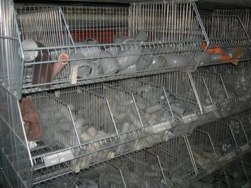 Scaffali in gabbie di filo metallico pieni di conigli grigi in un mercato coperto e scarsamente illuminato