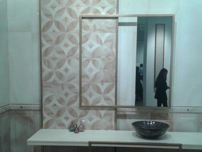 Mobile da bagno con specchio, carta da parati a motivi geometrici e due persone riflesse nello specchio.