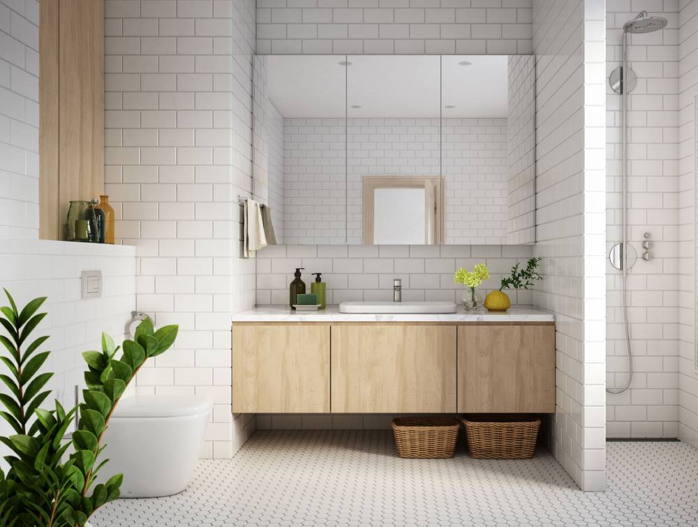 Bagno luminoso e moderno con mobile lavabo in legno, specchio rotondo, piastrelle bianche, pianta e box doccia.