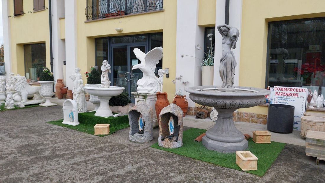 Esposizione all'aperto di statue di animali bianche e fontane a forma di abbeveratoio per uccelli davanti a un edificio giallo.