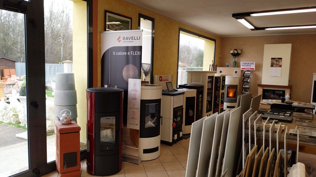 Showroom di caminetti con diverse stufe, inserti e modelli in esposizione, allestito in un luminoso spazio commerciale.