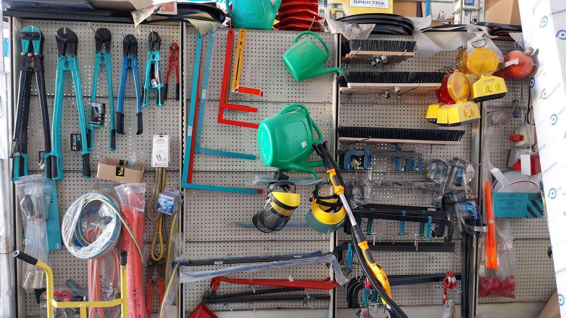 Parete attrezzata con attrezzi da giardinaggio e utensili manuali ben organizzati, con annaffiatoi verdi e accessori appesi.