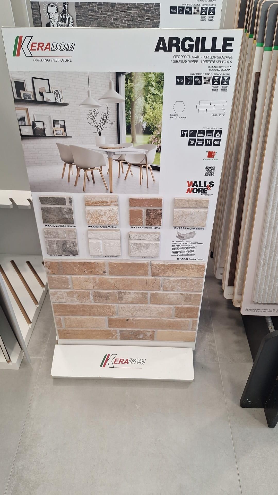 Cartello espositivo di piastrelle Argile in una corsia di un negozio, che mostra piastrelle da rivestimento con motivi beige e bianchi.