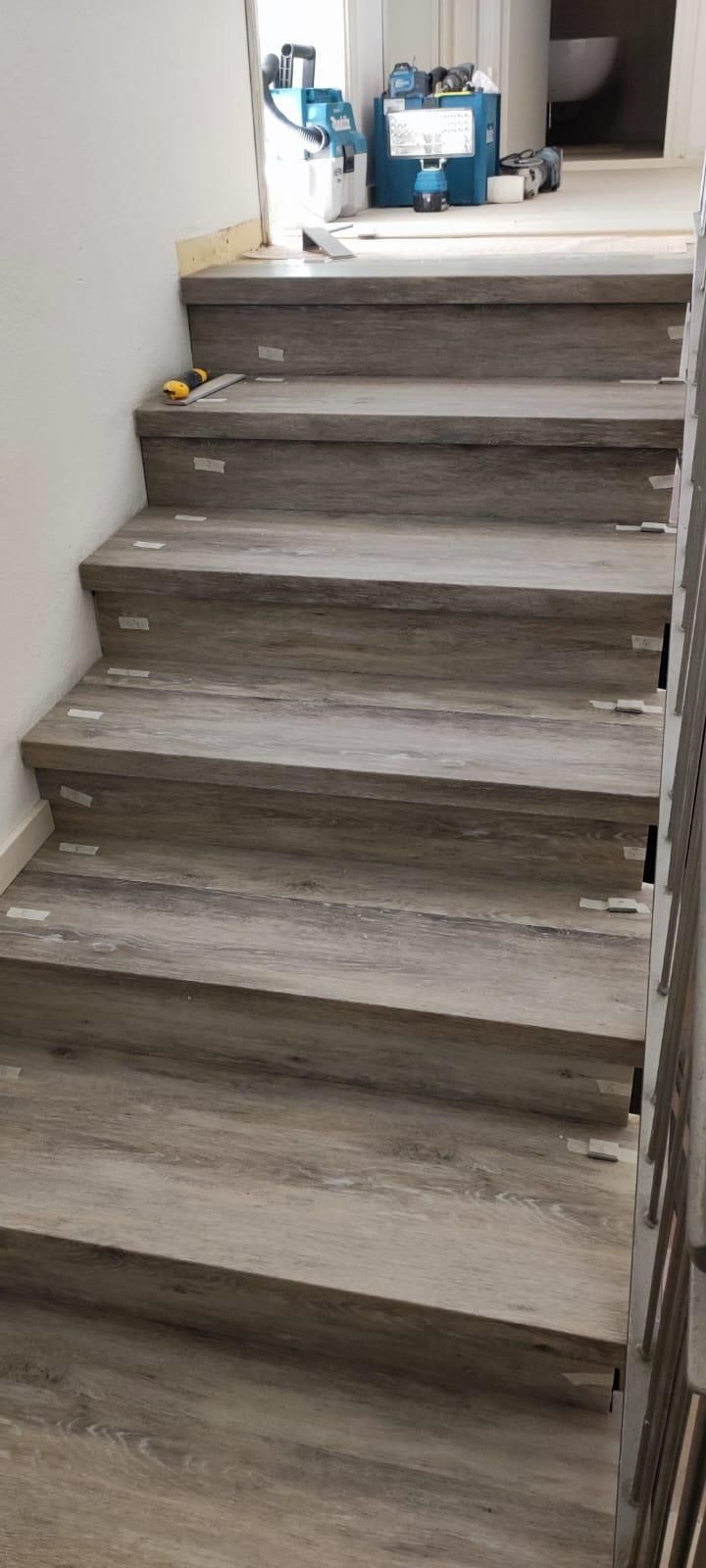 Scala in legno che conduce a un pianerottolo con secchi e attrezzi in cima.