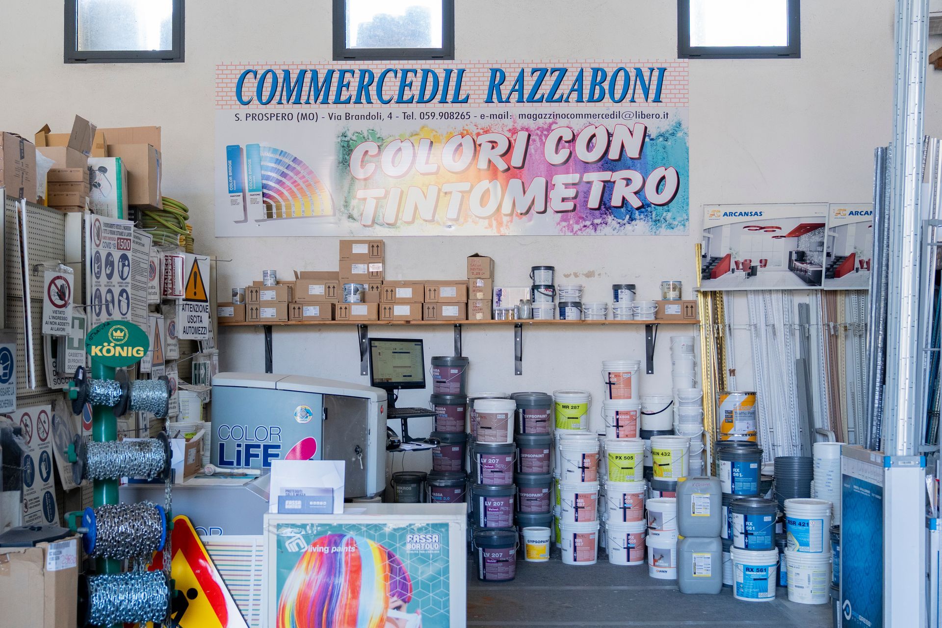 Espositore di un negozio di vernici con barattoli di vernice, cartelle colori e cartelli con la scritta 